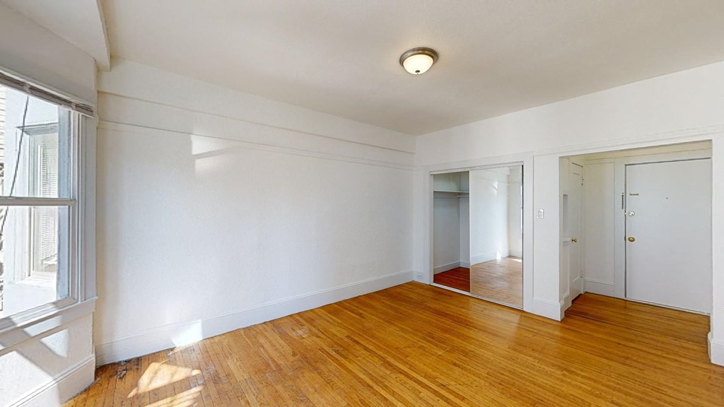 an empty living room with wood floors and white walls