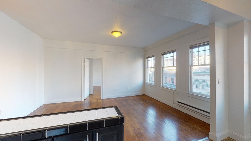 an empty living room with white walls and wood floors