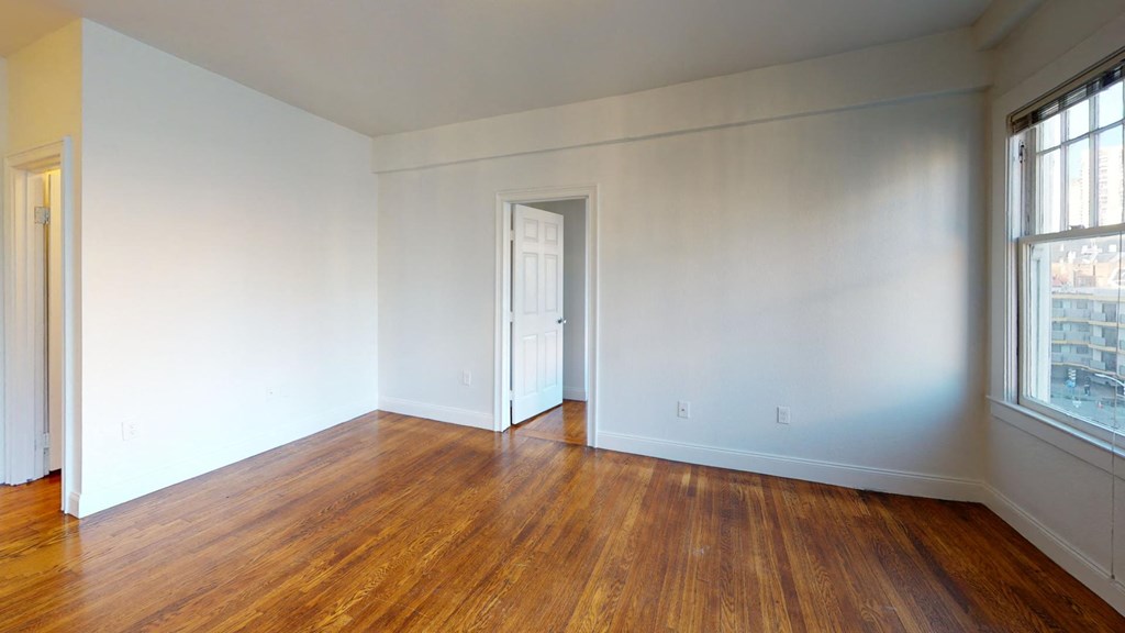 bedroom with white walls and wood flooring and a door