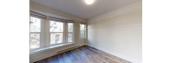 an empty living room with wood flooring and three windows