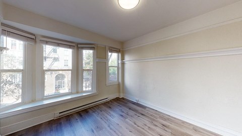 an empty living room with wood flooring and three windows