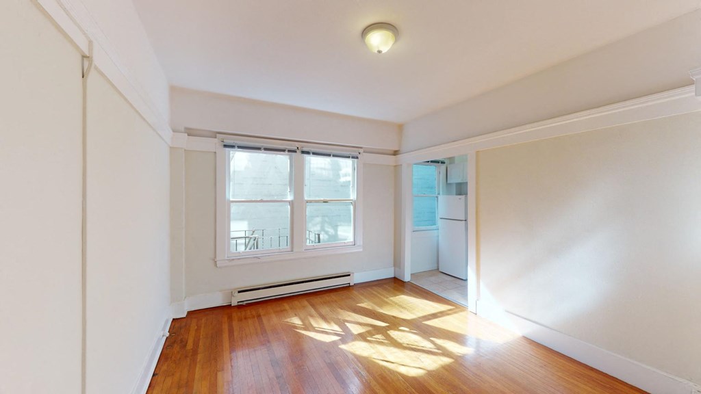 an empty living room with a large window and wood floors