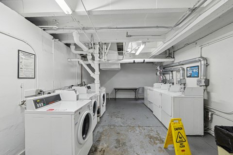 A yellow caution sign is in front of a large industrial washing machine.