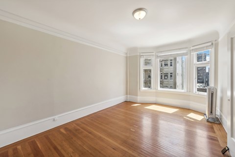 A room with wooden floors and a window overlooking a city.