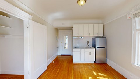 A kitchen with white cabinets and a refrigerator.