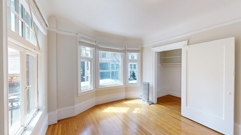 A room with white walls and wooden floors with a large open door.