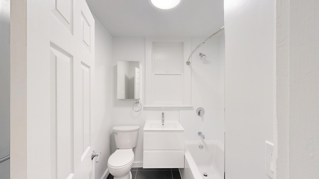 A white bathroom with a toilet, sink, and mirror.