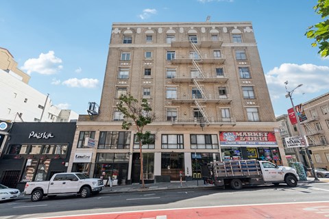 A white truck is parked in front of a building with a red awning.
