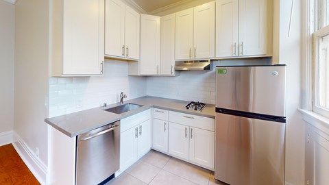 A kitchen with white cabinets and a stainless steel refrigerator.