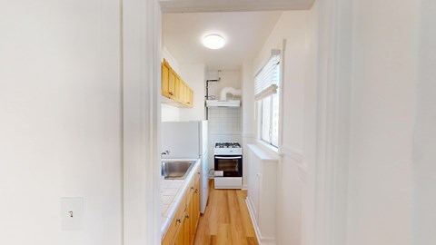 A long hallway with a kitchen area at the end.