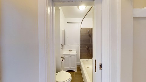 A white toilet is in a small bathroom with a white tub and sink.