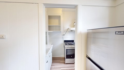 A white kitchen with a stove and a fridge.