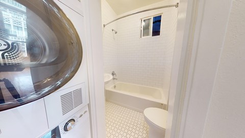A white bathroom with a tub, toilet, and washing machine.