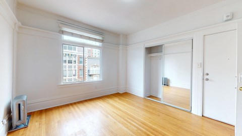 A room with a large window and wooden floors.