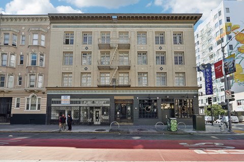 Two people walking on a sidewalk in front of a building.