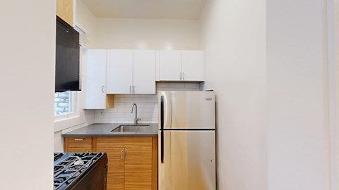 A kitchen with a stove top oven, refrigerator, and cabinets.