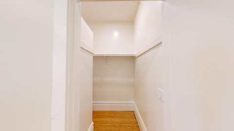 A hallway with a wooden floor and white walls.