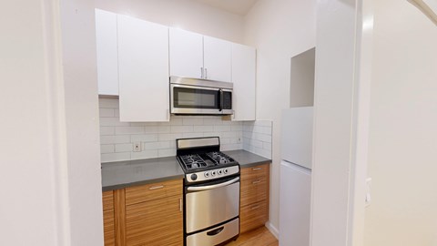 A kitchen with white cabinets and a stainless steel stove.