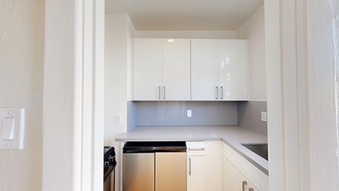 A kitchen with white cabinets and a black fridge.
