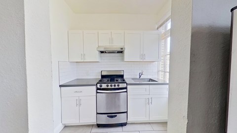 A modern kitchen with white cabinets and a stainless steel oven.