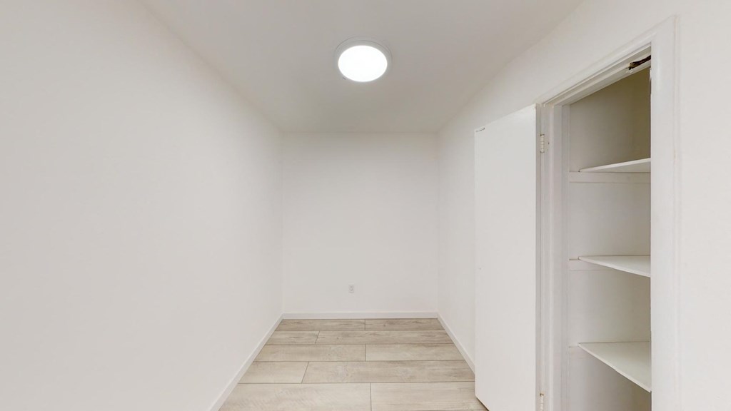 a room with white walls and a closet with shelves