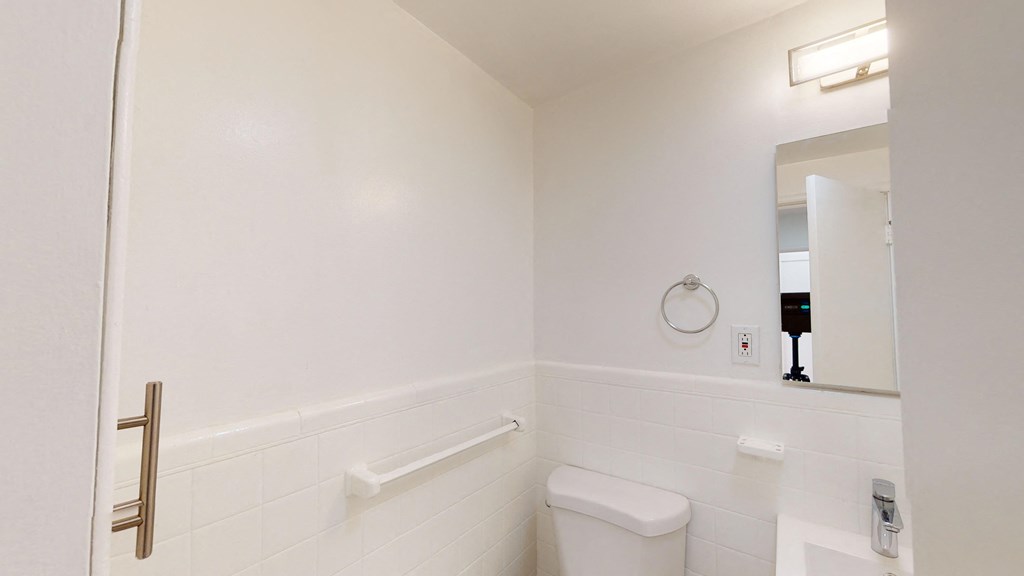 a white bathroom with a toilet and a mirror