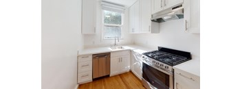 a kitchen with white cabinets and stainless steel appliances and a window