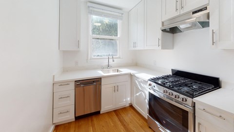 a kitchen with white cabinets and stainless steel appliances and a window
