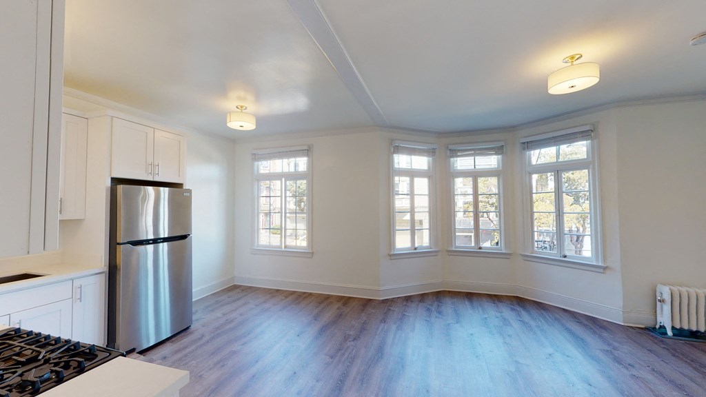 an empty kitchen with white walls and a stainless steel refrigerator