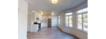 an empty kitchen with white cabinets and a large window