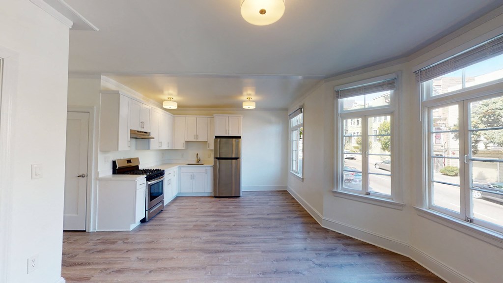 an empty kitchen with white cabinets and a large window