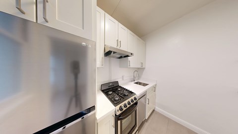 A modern kitchen with a stainless steel refrigerator and a black induction cooktop.