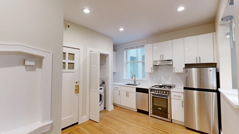 A modern kitchen with stainless steel appliances and wooden floors.