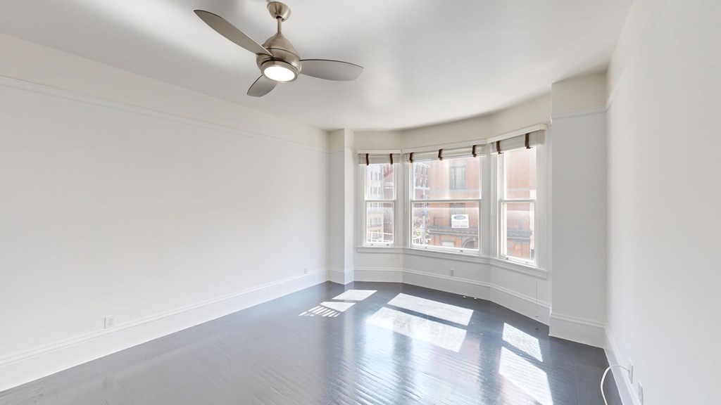 A room with a ceiling fan and a window with blinds.