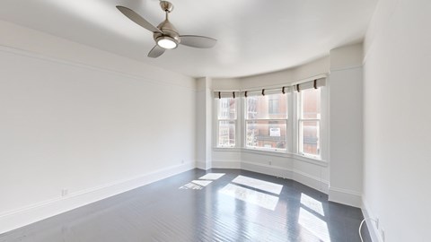 A room with a ceiling fan and a window with blinds.