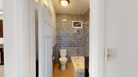 A bathroom with a toilet, sink, and tiled walls.