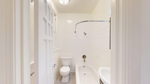 A white bathroom with a toilet, sink, and shower.