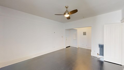 A room with a ceiling fan and a wooden floor.