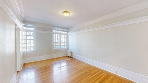 A room with wooden floors and white walls with a window.