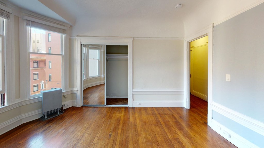 an empty living room with wood floors and white walls