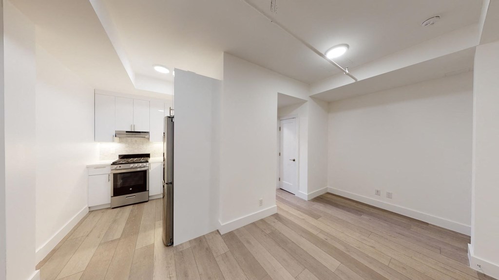 a renovated living room and kitchen with white walls and wood floors