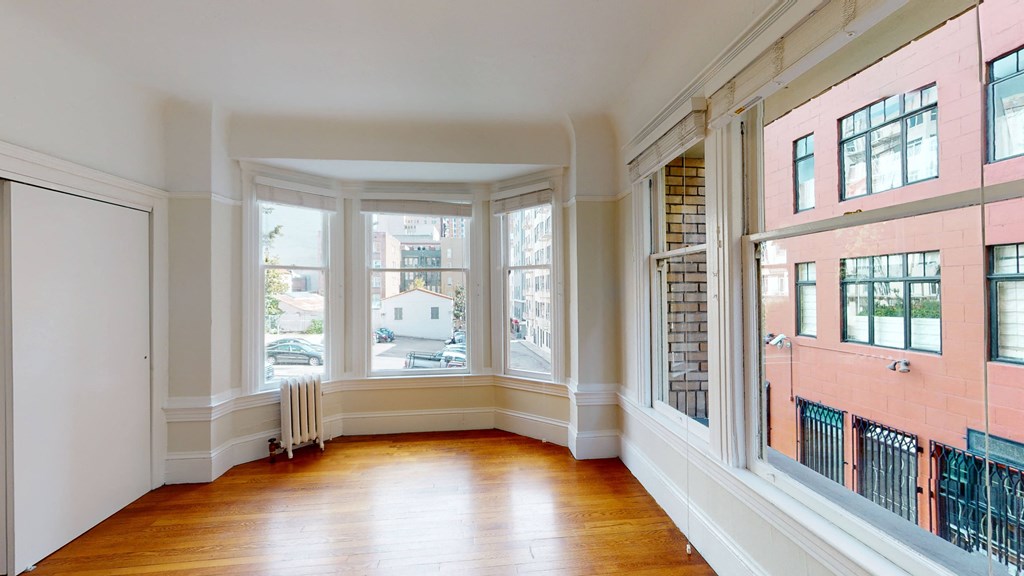 an empty living room with large windows and a wood floor