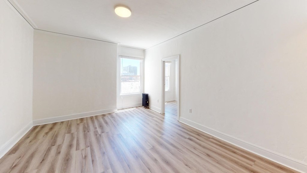 an empty living room with white walls and wood floors