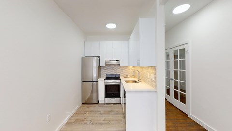 A kitchen with white cabinets and a stainless steel refrigerator.