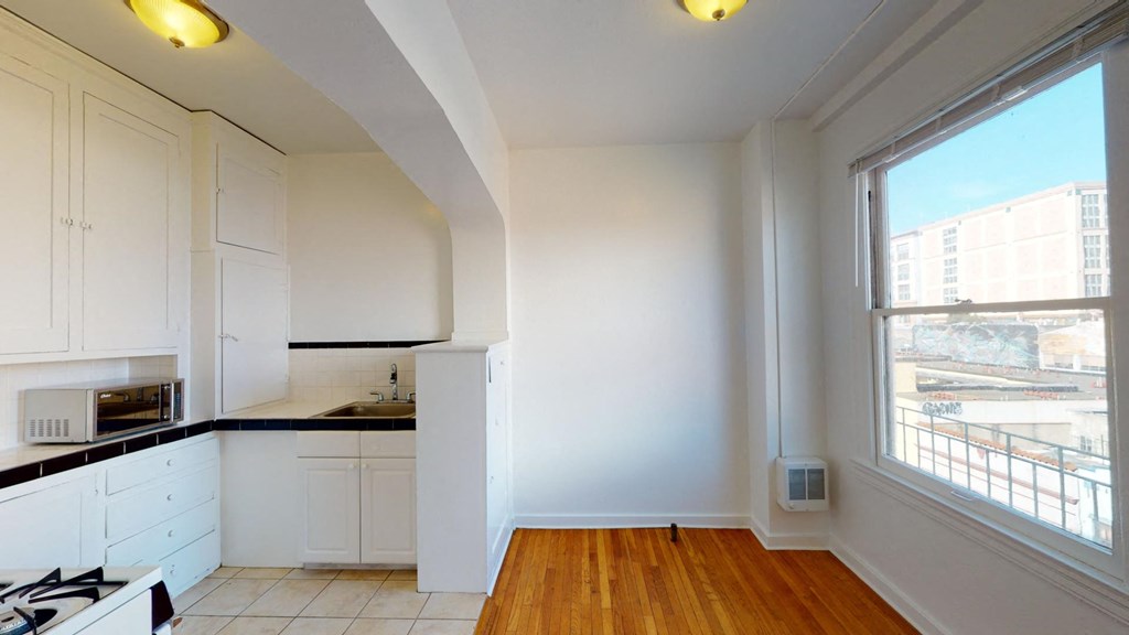a kitchen with white cabinets and a large window