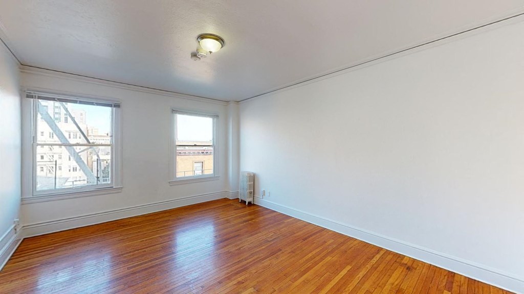 an empty living room with a hard wood floor and two windows
