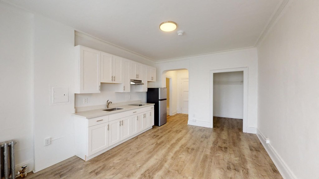 a renovated kitchen with white cabinets and a black refrigerator