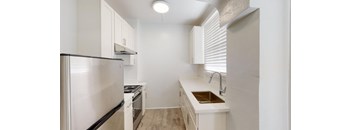 a white kitchen with a sink and a refrigerator