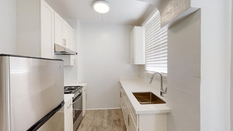 a white kitchen with a sink and a refrigerator