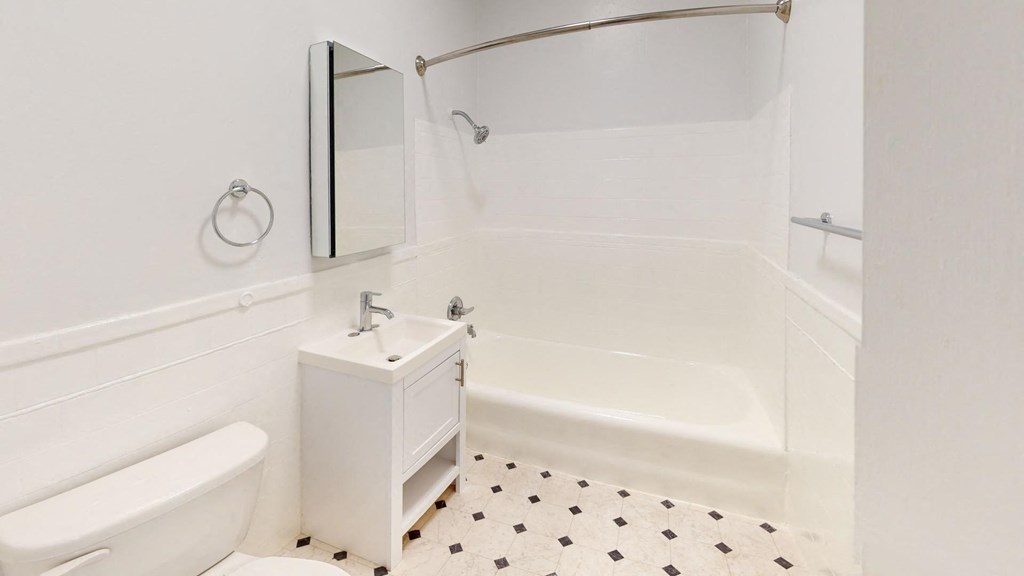 a white bathroom with a tub and a sink and a toilet
